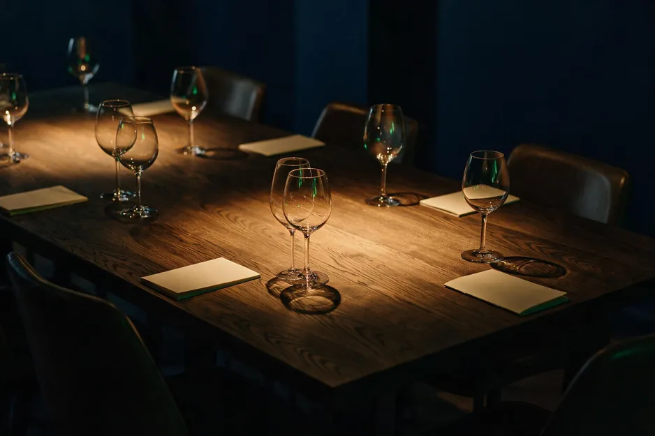 Mesa longa posta para um jantar, com taças e cadeiras vazias